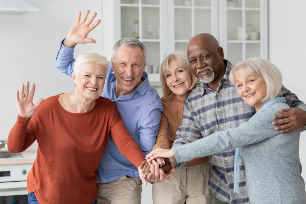 Senior living. Multiracial group of senior people friends holding hands and waving