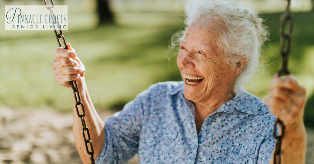 A cheerful senior woman on a swing at a playground. Benefits of memory care services for seniors with cognitive decline.